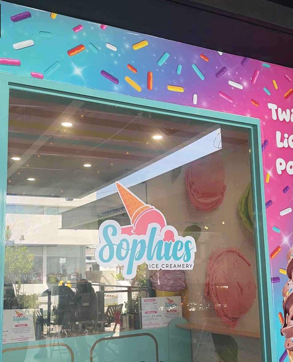 Close-up of the Sophie’s Ice Creamery window with the logo, giant scoop artwork inside and the sprinkle mural above
