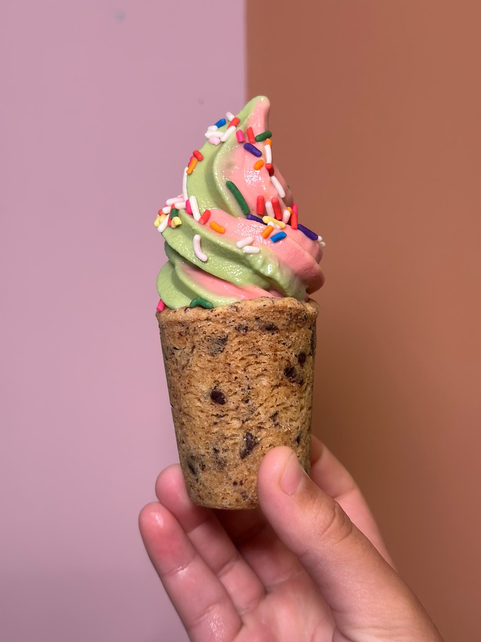 Una mezcla de matcha y fresa cubierta de chispitas de colores, servida en un vaso de galleta con chispas de chocolate