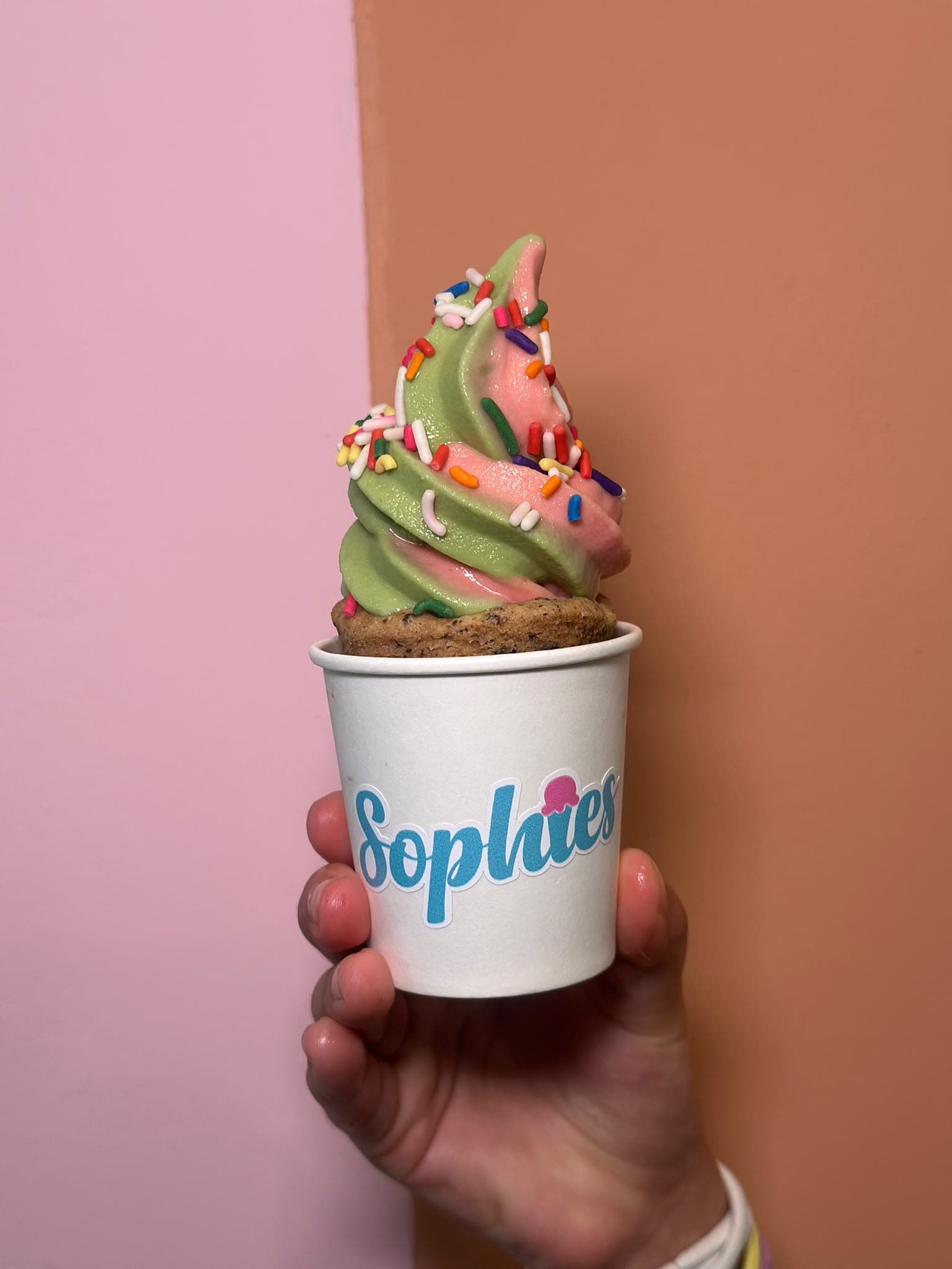 Una mezcla de matcha y fresa con chispitas de colores en un vaso de galleta, dentro de un vaso de papel de Sophie’s